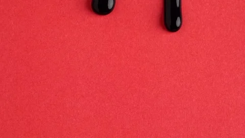 Liquid drops of bright black paint color flowing on the red surface. Macro .. Stock Footage 250517018