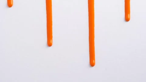 Liquid drops of orange paint color flowing on the white surface. Macro shot.. Stock Footage 249929201