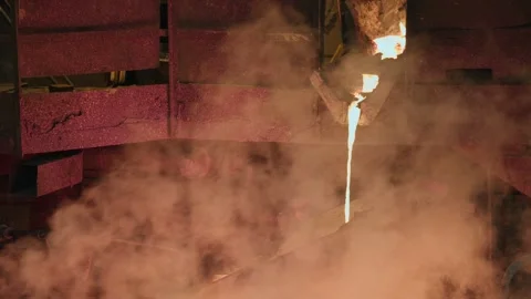 The liquid glowing metal pours in a thin stream into the distribution ladle Stock-Footage 301390871