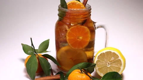 Liquid ice cube lemon orange tea with slice green leaf cinnamon stick in transpa Stock Footage 144712200