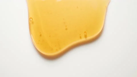 Liquid light honey flows down on a white surface. Close up. Vídeo Stock 148468681