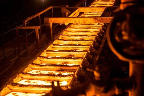Liquid metal in the molds on the conveyor belt at the steel mill Stock Photos