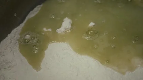 Liquid mixture of water and flour gradually combines in a mixing bowl, showing Vídeo Stock 331755422