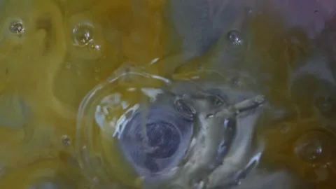 Liquid raw beaten chicken egg mixture drips and flows across the bottom of .. Stock Footage 344112530