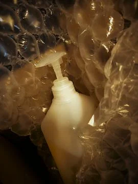 Liquid soap dispenser bottle inside protective bubble wrap. Fotos Stock