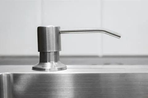 Liquid soap dispenser built into modern metal sink Stock Photos