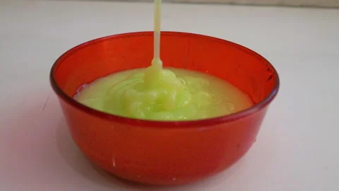 Liquid soap is poured into a red bowl, light green acrylic liquid paint Stock Footage 336557009