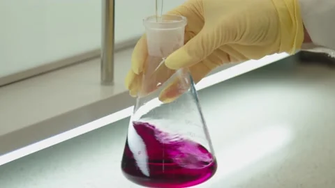 The liquid substance is dropping to the glass bulb and the hand of scientist in Stock Footage 199686926