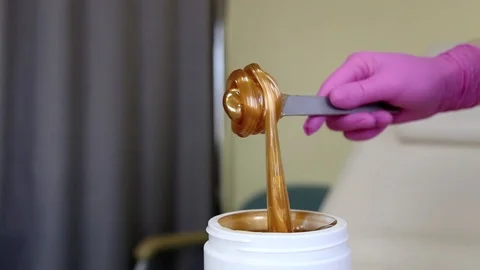 Liquid sugar for skin epilation. Close up shot. depilation and beauty concept - Stockbeeldmateriaal 125756444
