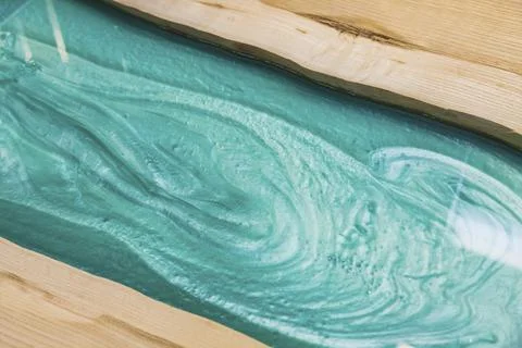 Liquid turquoise epoxy on the kitchen table in the workshop Stock Photos
