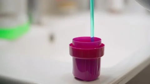 Liquid washing machine powder being poured into a measuring cup, close-up Stock Footage 324517020