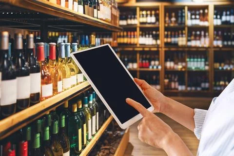 Liquor store manager using digital tablet in front of half of wine bottles... Stock Photos