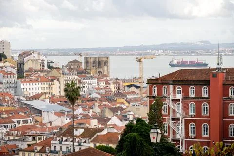 Lisbon rooftops and river view with cargo ship and crane Stock Photos