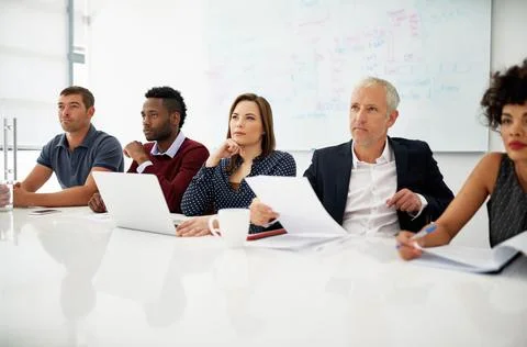 Listening carefully to the ideas put forth. a group of businesspeople listening Stock Photos