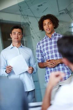 Listening to constructive feedback. Two attractive casual businessmen giving a Stock Photos