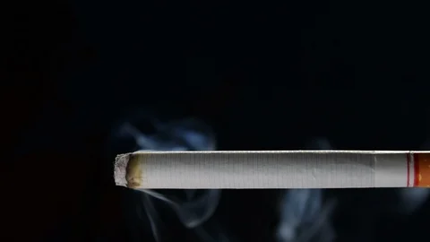 Lit and burning cigarette with smoke on black background . Stock Footage 125541982