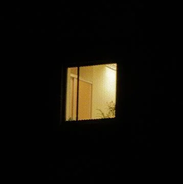 Lit apartment window at night Photos
