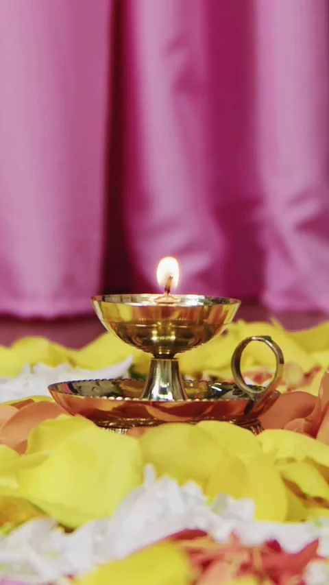 Lit brass lamp sits on yellow white flower petals Stock Footage 331773157