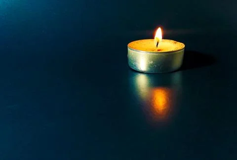 A lit candle on a blue background Foto stock