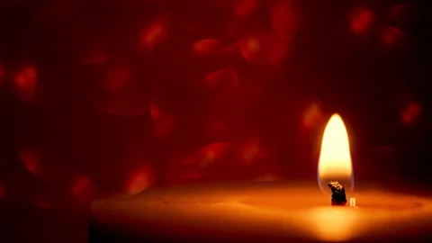 Lit candle on a red shimmering background Video stock 144135357
