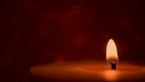 Lit candle on a red shimmering background Video stock 144795035