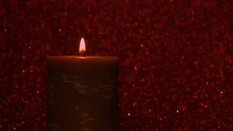Lit candle on a red shimmering background Video stock 144949846