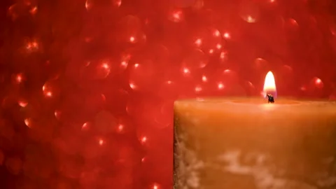 Lit candle on a red shimmering background Video stock 145175933