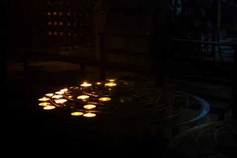 The lit up candles stood by prayers in the darkness of a church room at Notre Stock Photos