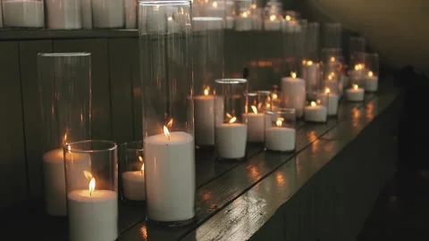 Lit candles in white flasks stand on wooden benches, decor for a wedding or Stock Footage 315897543
