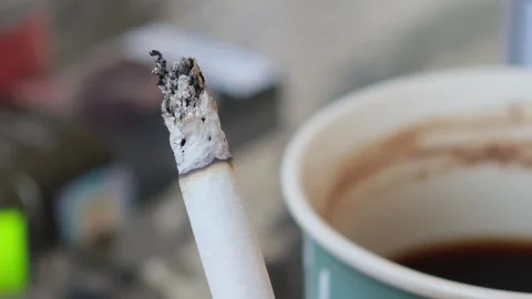 Lit cigarette and disposable coffee cup Vidéo 315359355