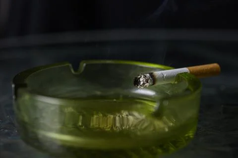 Lit cigarette burning in ashtray close up Stock Photos