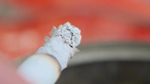 Lit cigarette burning slowly with orange background Видео 307865667
