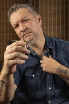 A lit cigarette is in the foreground, and a 48 year old Brazilian man is in.. Stock Photos