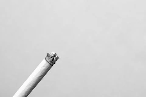 A lit cigarette on gray background closeup Stock Photos