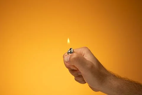 Lit cigarette lighter and flame held in hand by Caucasian male hand. Close up Foto stock