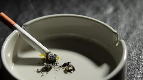 Lit cigarette lying on an empty white ashtray . Stock Footage 125544585