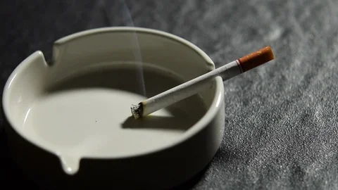 Lit cigarette lying on an empty white ashtray . Stock Footage 125544621