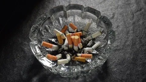 Lit cigarette with smoke lying on an ashtray . Stock Footage 125546204