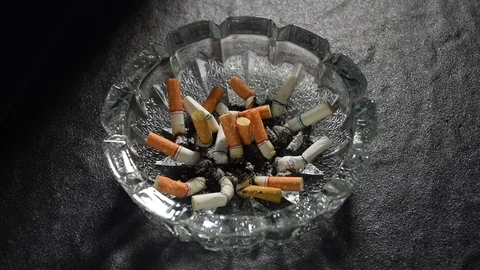 Lit cigarette with smoke lying on an ashtray . Video stock 125546208