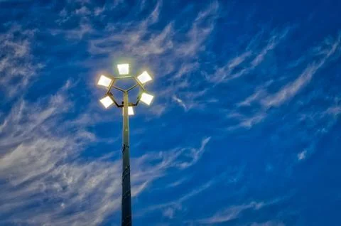 Lit hexagonal streetlight under dramatic sky. Fotos Stock