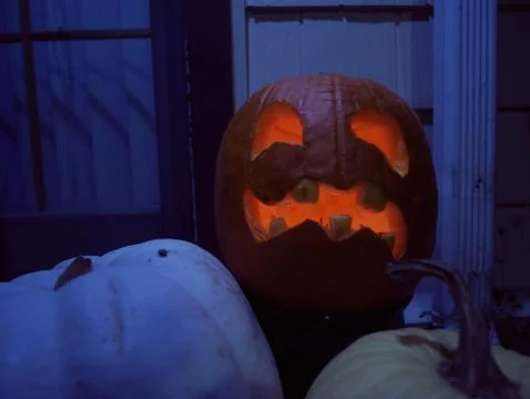 Lit Jack O'Lantern and Pumpkins against Window at Night Stock Photos
