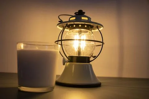 Lit lantern with yellow light and candle next to it, home evening Stock Photos