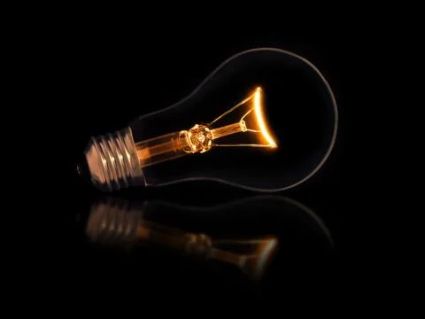 Lit light bulb on black background Фото