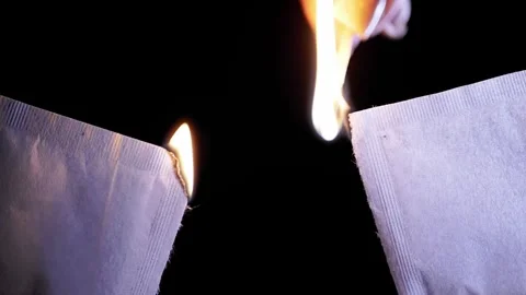 Lit Match Igniting Torn Edges Of White Paper Packets On Black Background 库存影片 330300795