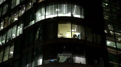 LIT OFFICE WINDOW WITH MAN PREPARING TO LEAVE AFTER WORK Vídeo Stock 61282970