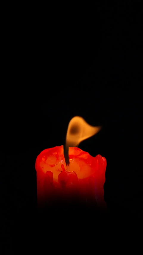 Lit red candle with a flame developing in the wind on black background. Stock Footage 303836552