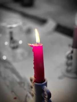 Lit red candle with warm flame and festive bokeh background Stock Photos