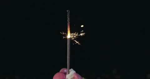 A lit sprinkle candle on top of a cake with pink frosting and sprinkles Stock Footage 309659423