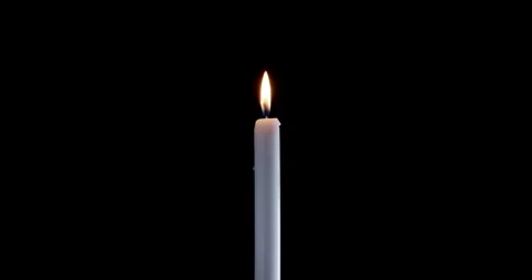 Lit taper candle on a black background. The golden flame of the candle slowly Stock Footage 347600860