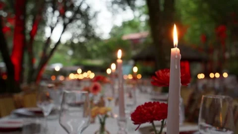 Lit Taper Candles And Red Gerbera Flowers On Outdoor Banquet Table Stock Footage 342859604